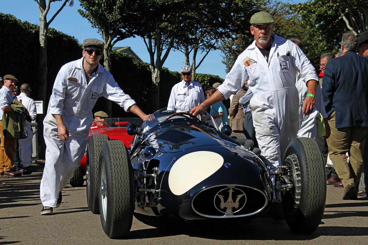 Maserati 250F going out at the Revival. Four blokes in white overalls, no barriers, and nothing on the circuit built aft